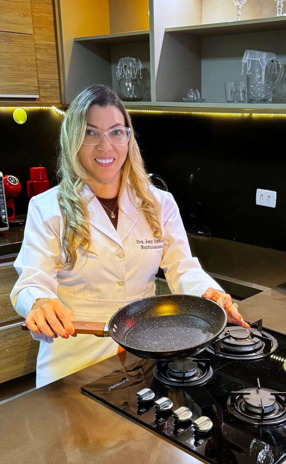Dra. Josy Dantas cozinhando, com uma frigideira no fogão